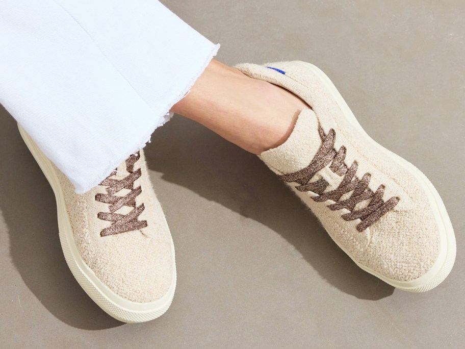 woman wearing a pair of white fuzzy sneakers with metallic brown laces