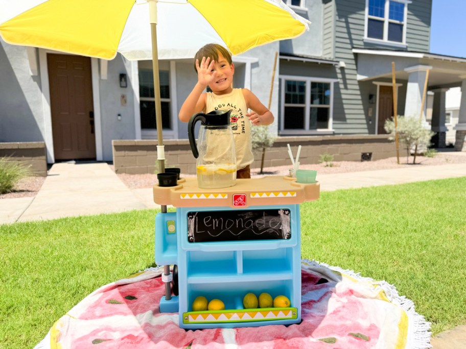 little boy standing behind a Step 2 Alex's Lemonade Stand