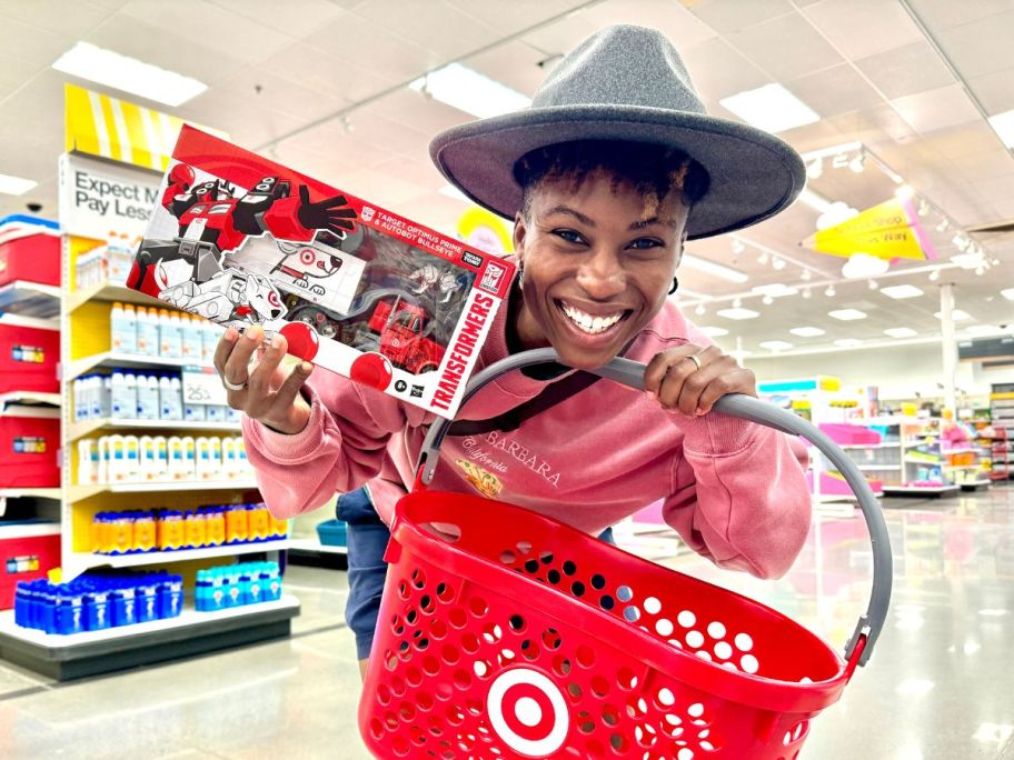woman holding target basket and Transformers Target Optimus Prime and Autobot Bullseye Action Figure Set box in store