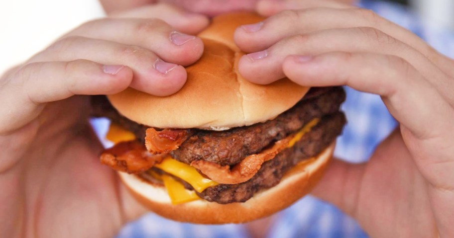 person about to take a bite from a Wendy's Baconator