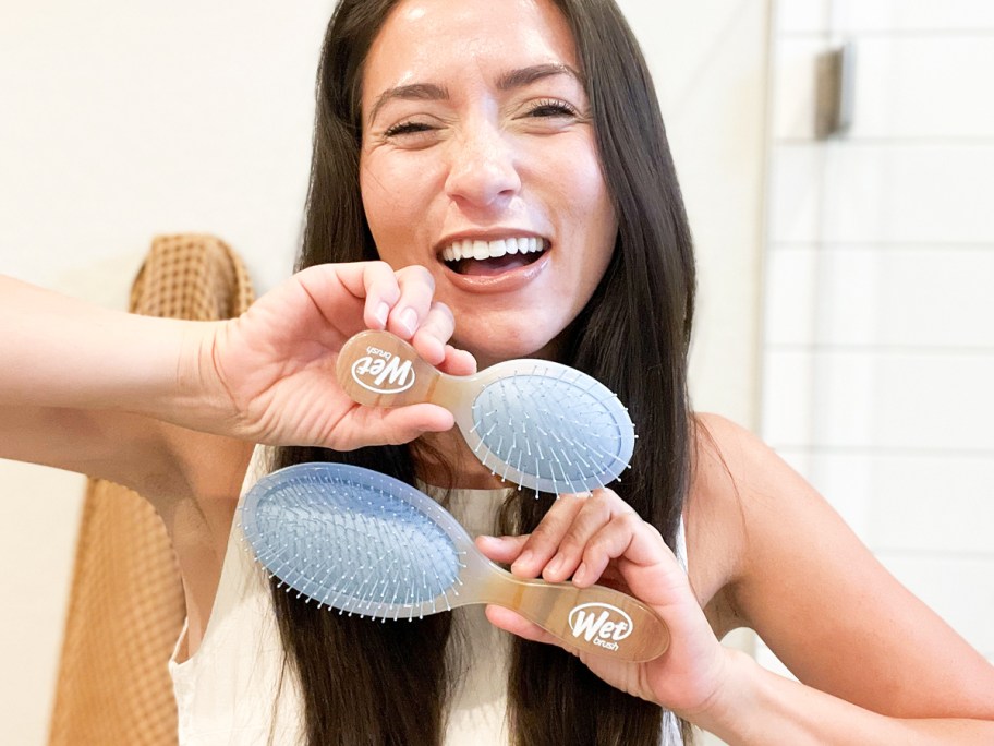 woman holding up original and mini wet brush hair brushes