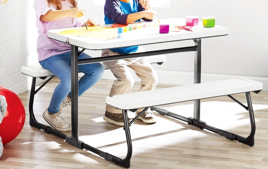 two kids doing art project on white picnic table