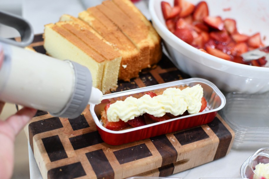 adding whipped cream to mini strawberry shortcake