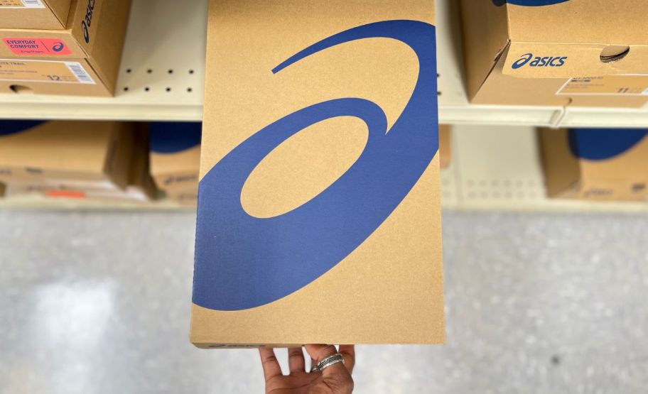 a woman grabbing an asics shoe box off a store shelf