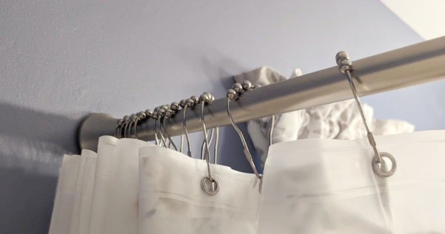 close up view of shower curtain liner hanging from metal rings