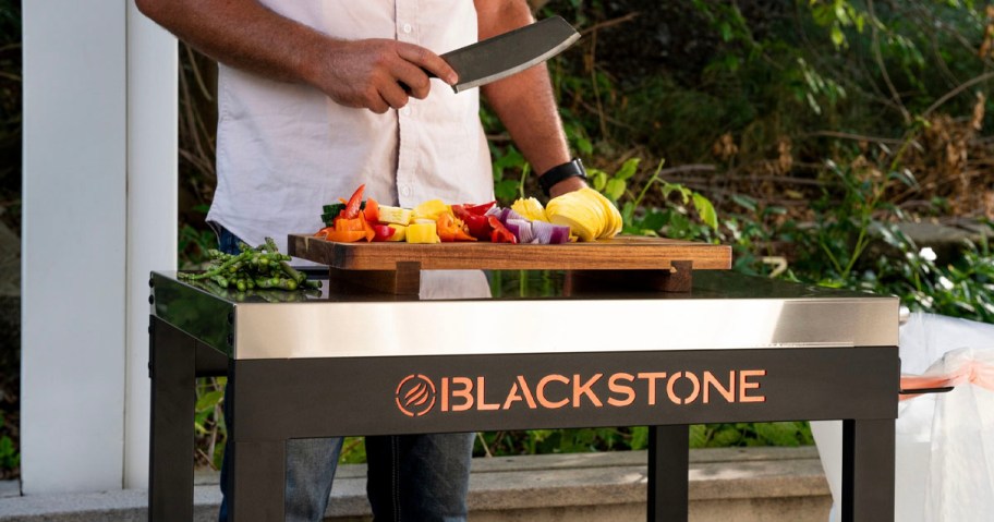 man cutting veggines on top of blackstone prep cart