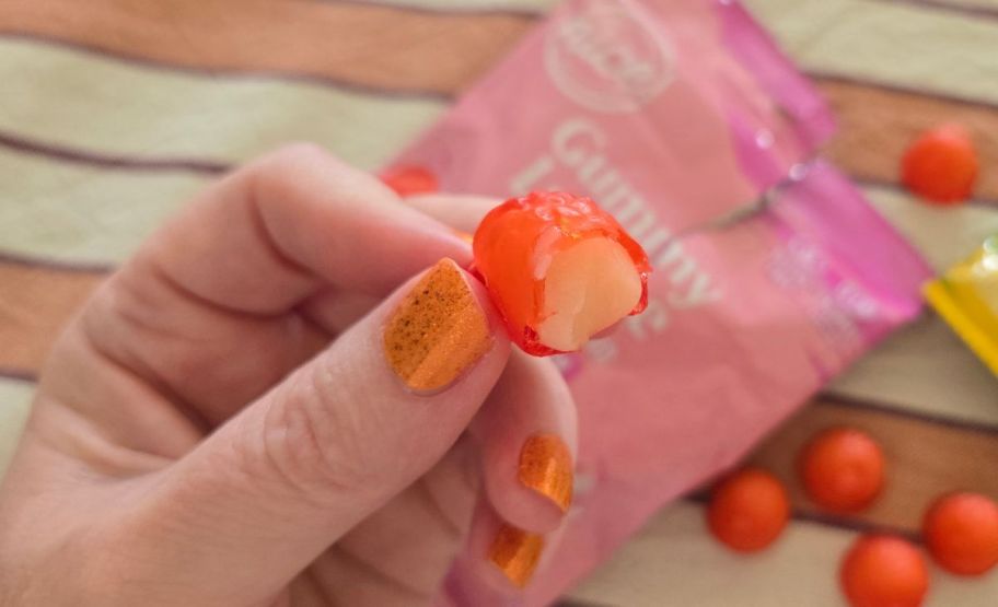 womans hand holding a piece of peelable lychee gummy candy