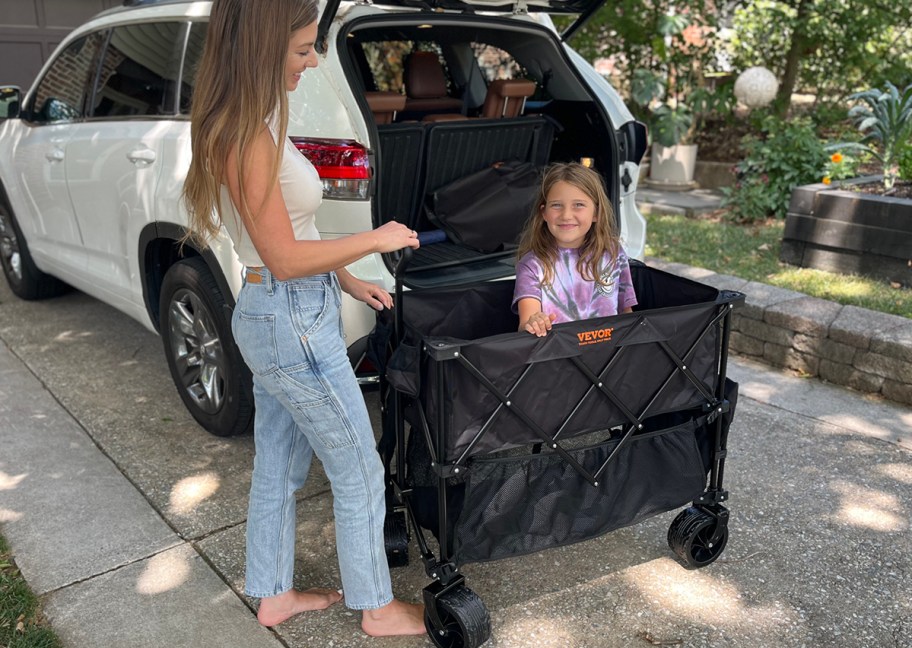 woman with child inside black wagon near car