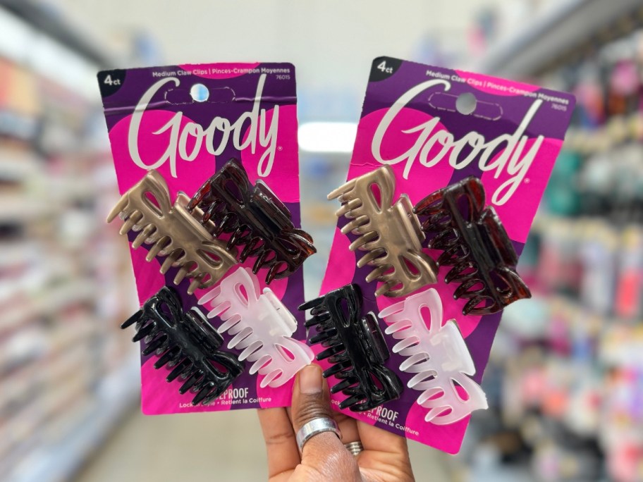 hand holding two 4 packs of Goody Hair Claw Clips on the paper packaging