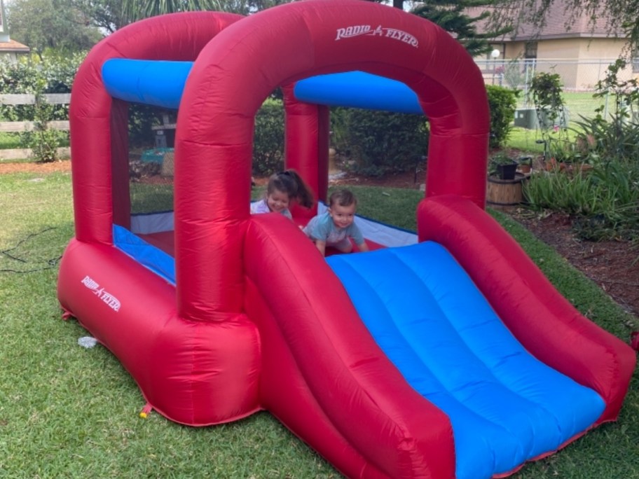 bright red and blue Radio Flyer kid's bounce house in a backyard with kids playing inside