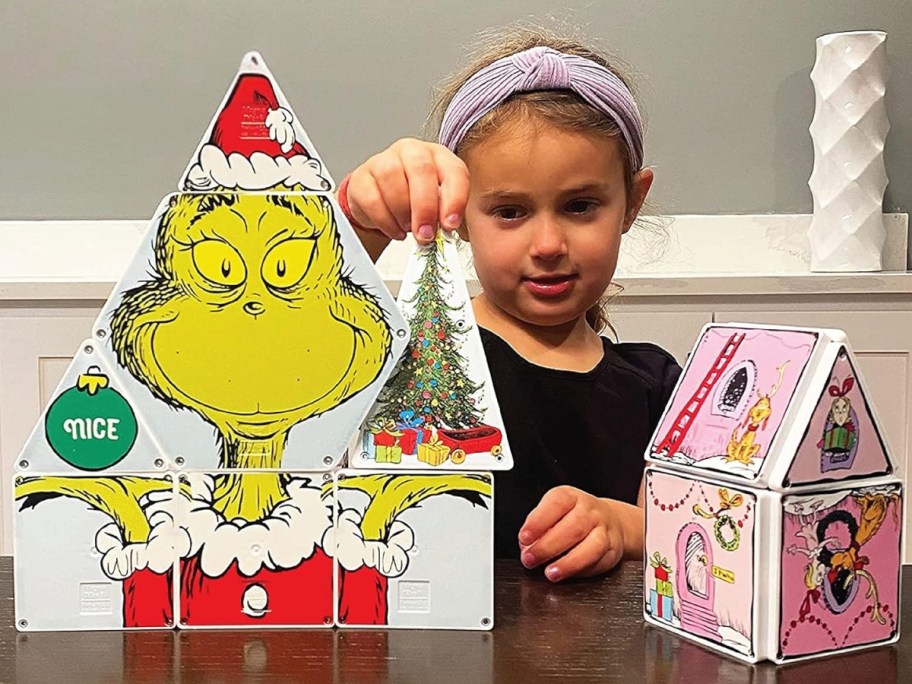 little girl behind a set of Magna-Tiles featuring How the Grinch Stole Christmas images