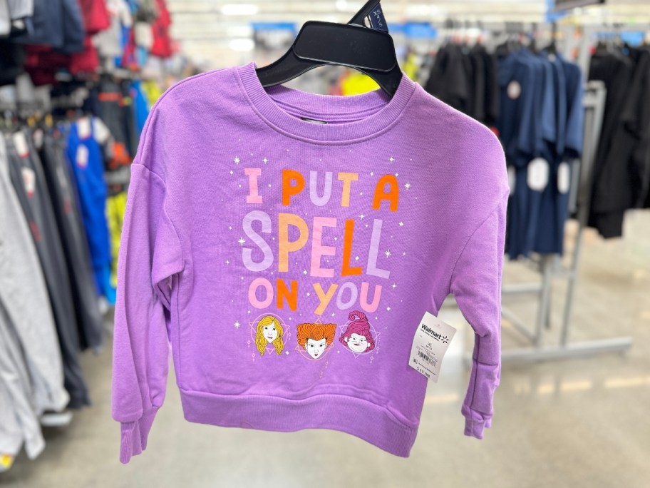 hand holding a girl's purple Hocus Pocus Sweatshirt that says "I put a spell on you"