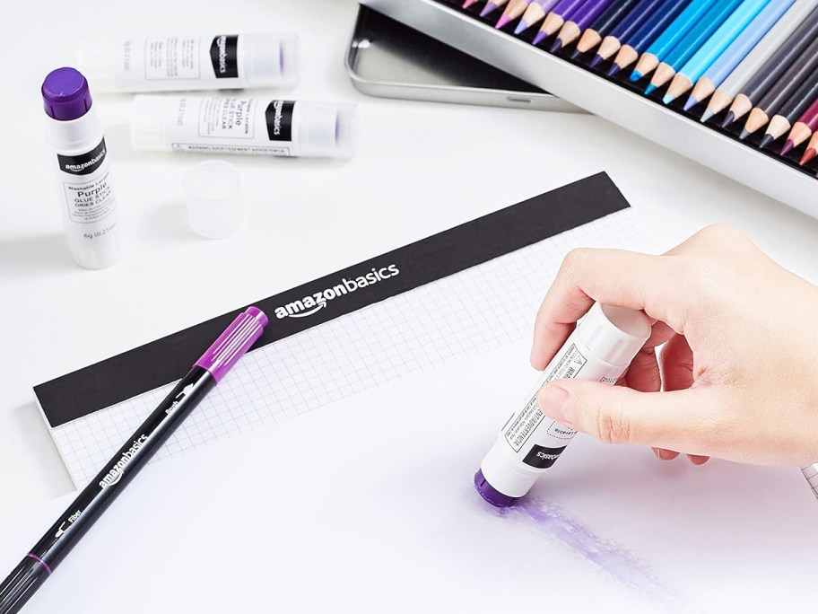 person using purple glue stick on white paper