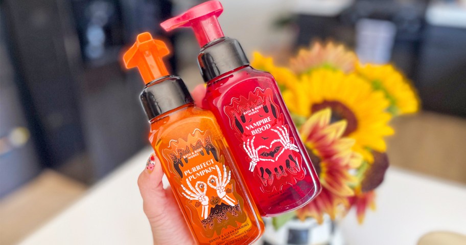 hand holding up orange and red bottles of Bath & Body Works Halloween Hand Soaps