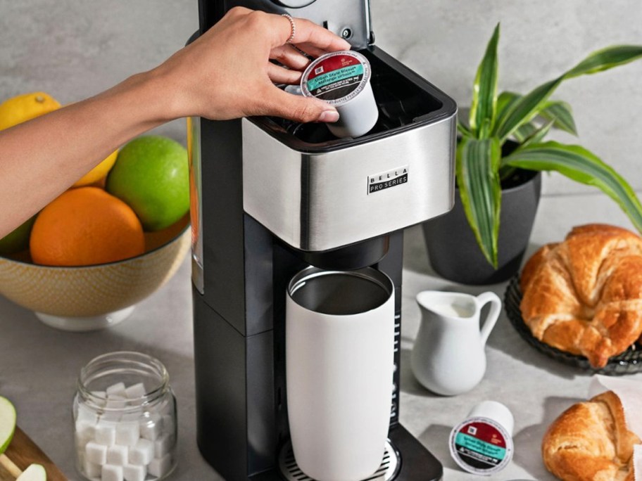 person placing k-cup into top of coffee maker