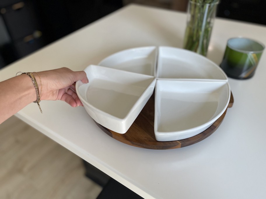 hand holding triangular white plate from lazy susan serveware on white countertop