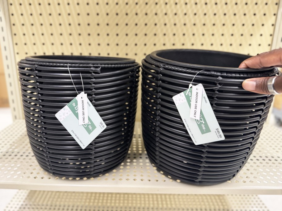 hand touching black planters on store shelf