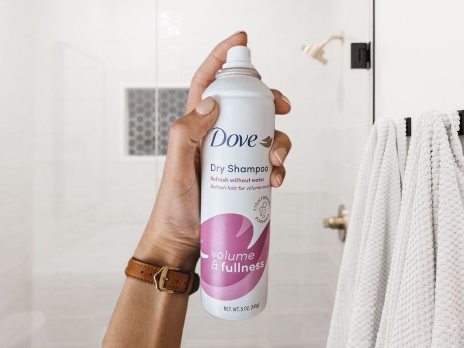 hand holding Dove Dry Shampoo Volume & Fullness for Oily Hair for Refreshed Hair 5 oz in bathroom