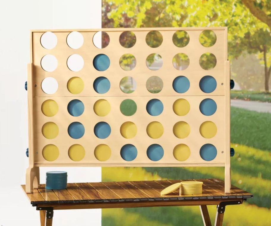 A large, wooden, Connect 4 Game on a table 