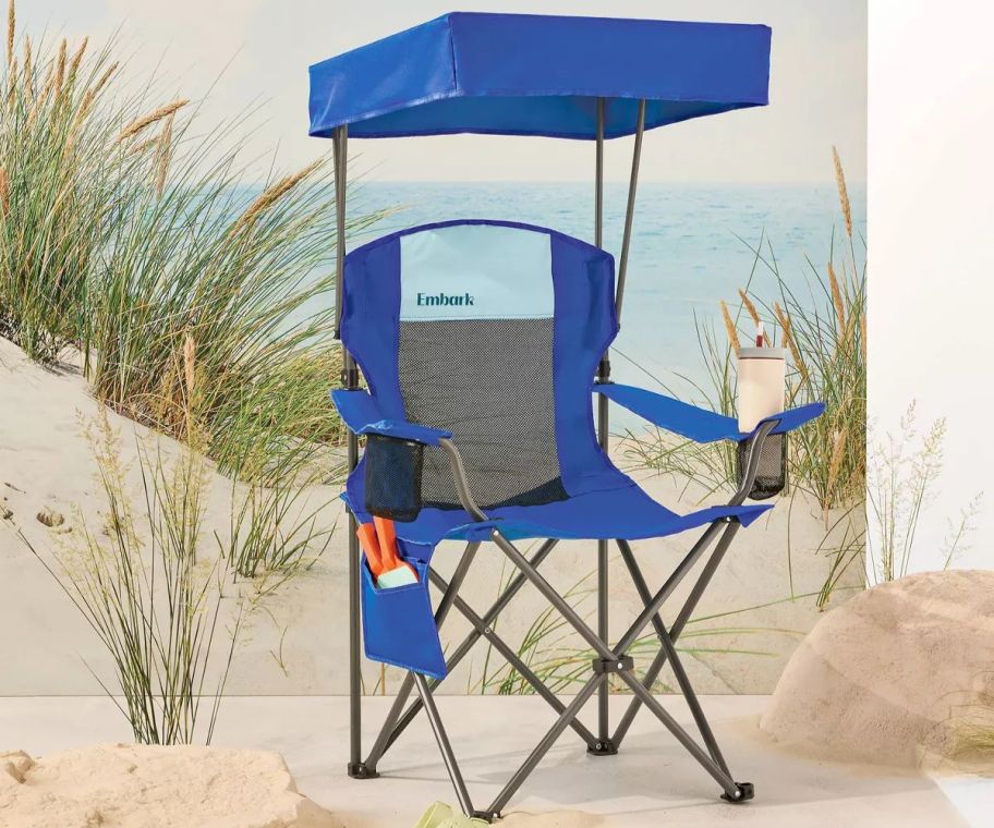A blue camping chair with a canopy on the beach 