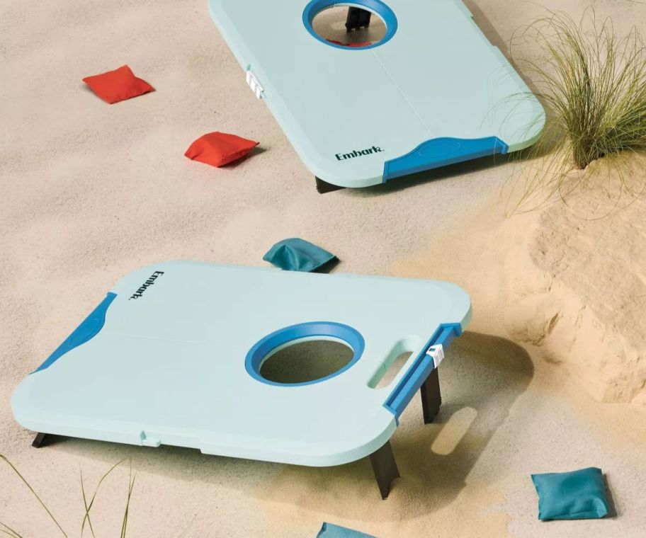 A plastic corn hole game on a beach