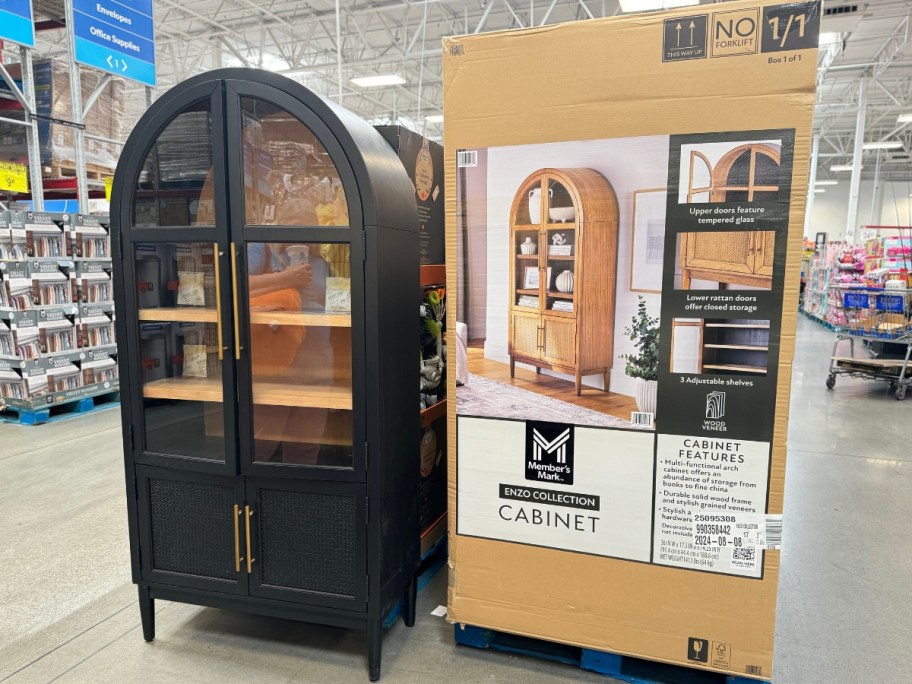 black arched storage cabinet next to a natural brown finish one in a box at Sam's Club