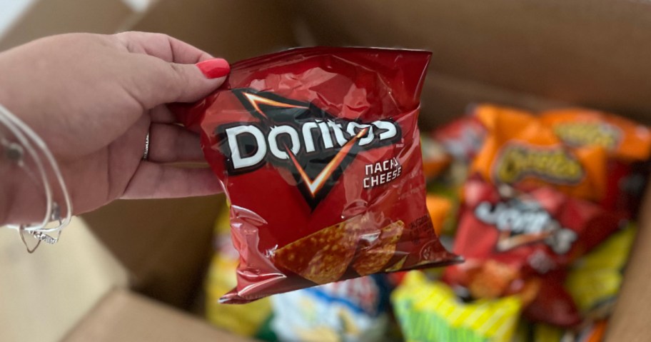 woman holding up small bag of Doritos chips