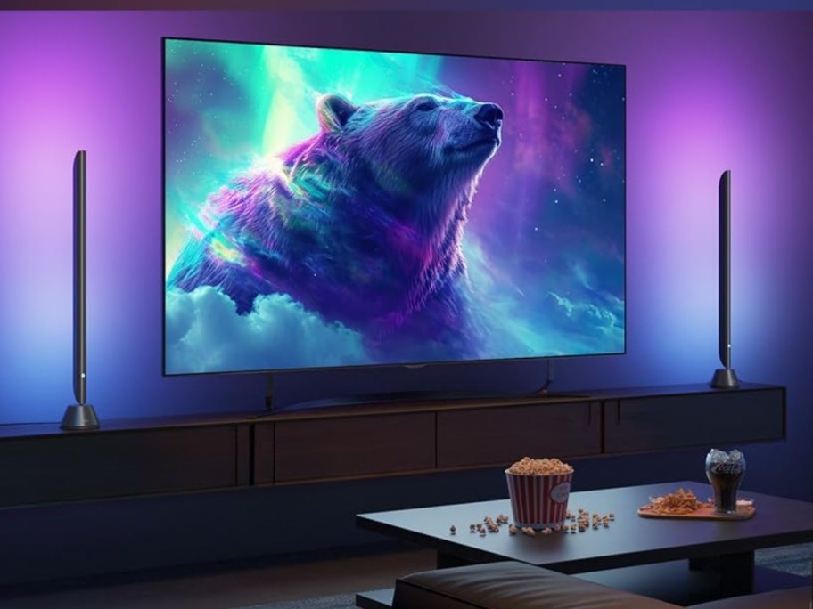 tv on wall with a light bar underneath, colorful lights around it