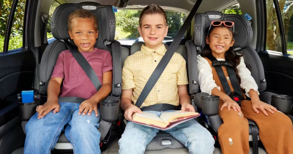 Three different aged kids sitting in backseat of car in gray car seats