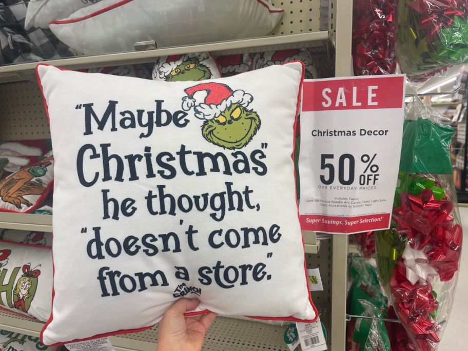 Grinch Maybe Christmas Pillow being held by hand in store