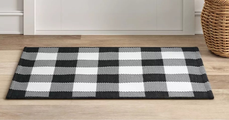 a black and white checkered small rug in front of a white door