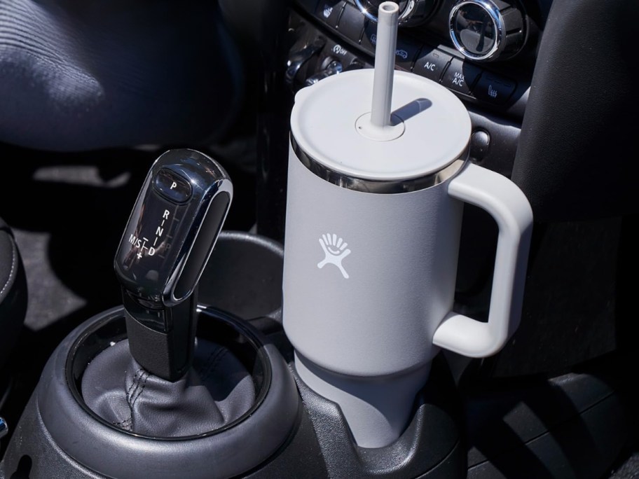 light grey large Hydro Flask travel tumbler with handle and straw in a car's cupholder