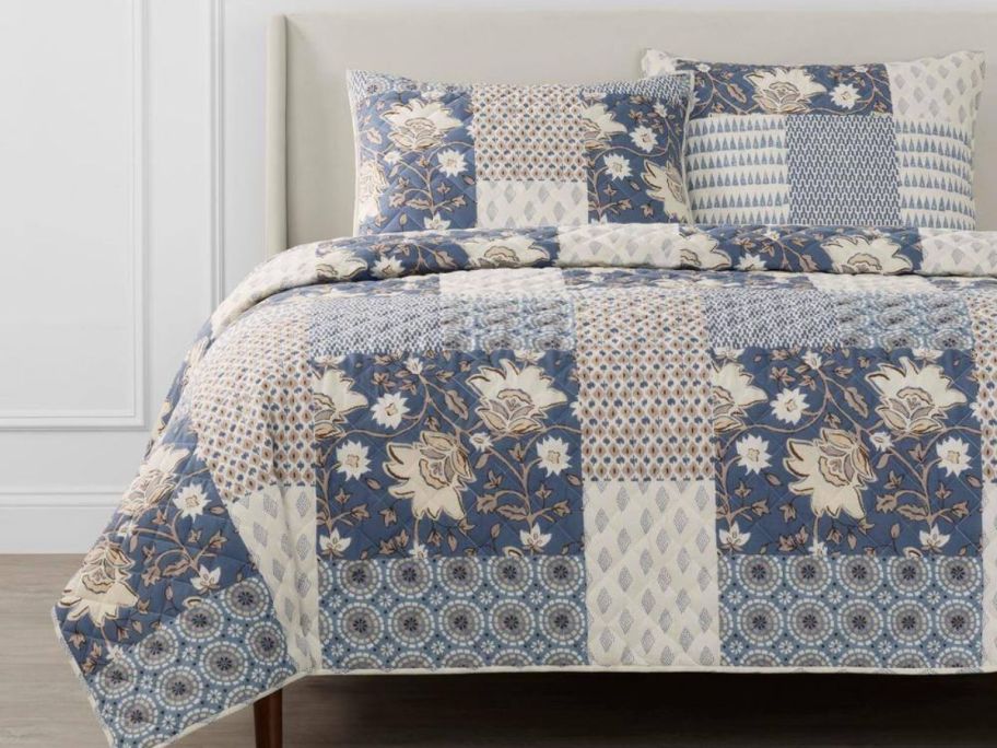 A bed with a blue, floral patchwork onlineforter