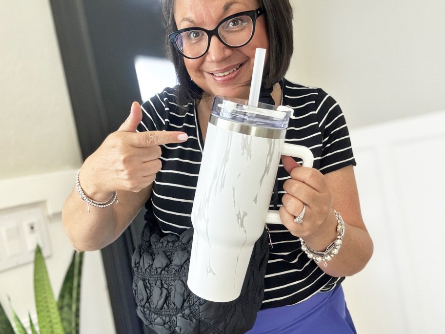 woman holding up and pointing to a marble print 40oz tumbler