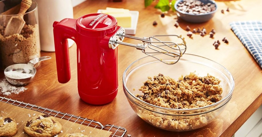 red kitchenaid mixer next to bowl of cookie dough