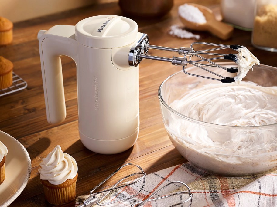 white KitchenAid Cordless Hand Mixer next to bowl of whipped cream