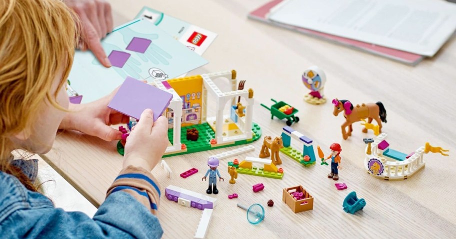 girl building lego horse stable