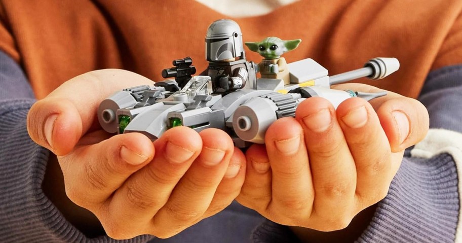 child's hands holding lego star wars ship