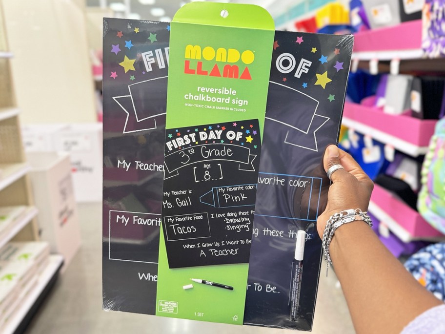 hand holding up a chalkboard first day of school sign