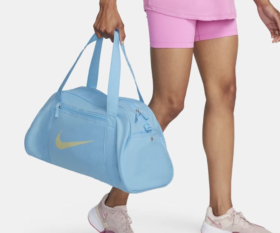 a woman carrying a light blue nike duffle bag