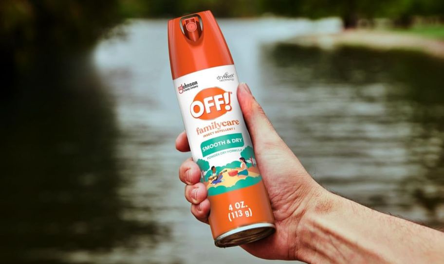 a hand holding a can of bug repellent