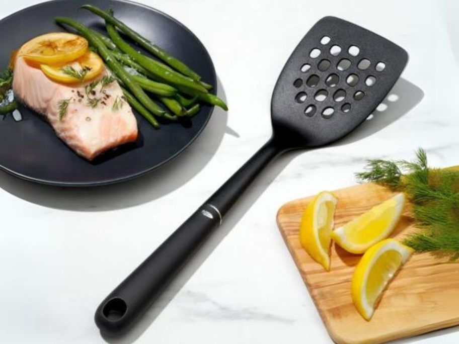 OXO Good Grips Nylon Square Turner on counter sitting in between plated meal and cutting board with lemons on it