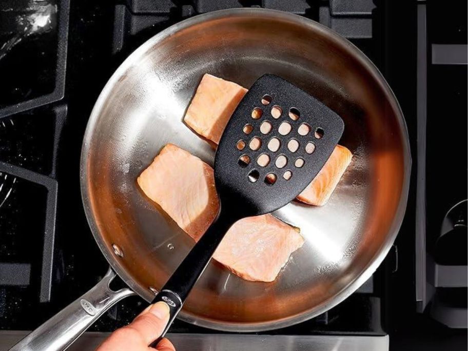 hand using OXO Good Grips Nylon Square Turner on salmon in pan