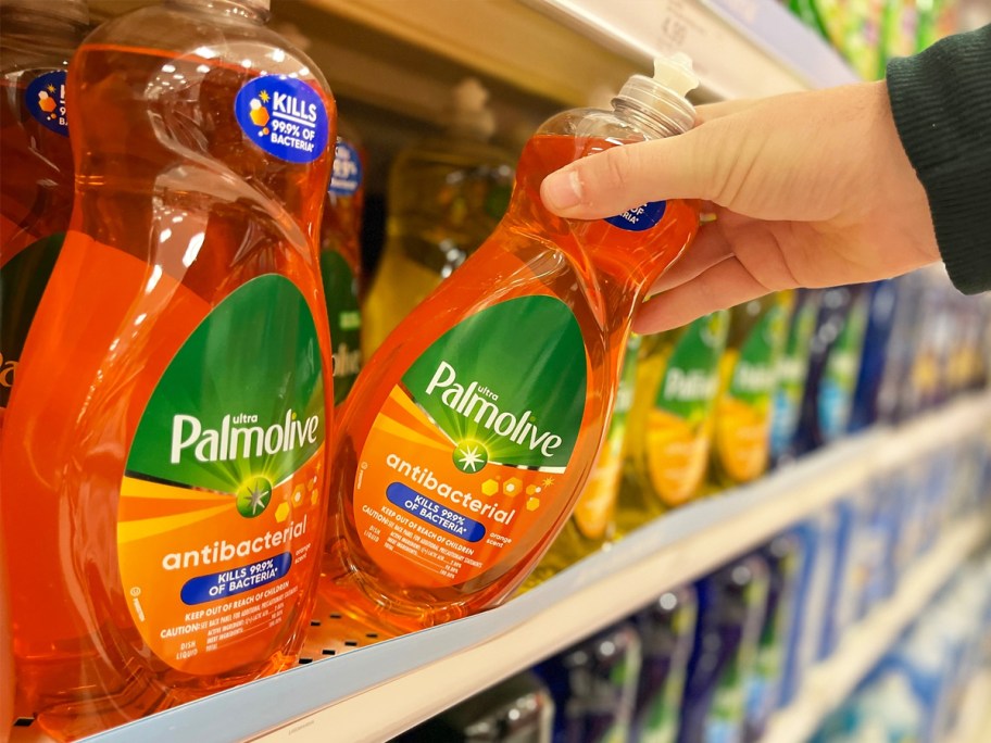 hand grabbing bottle of orange Palmolive dish soap from store shelf