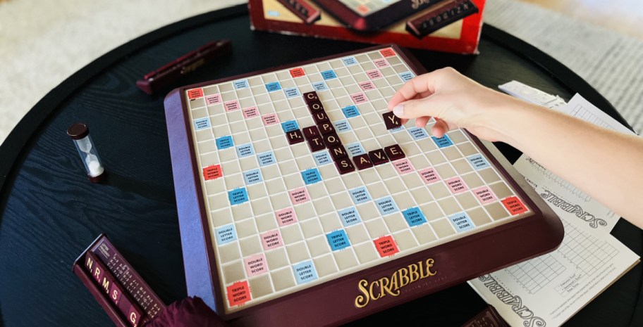 hand placing a tile on The Scrabble Board Game