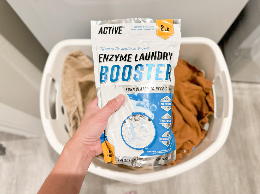 hand holding active enzyme laundry booster bag over basket of laundry