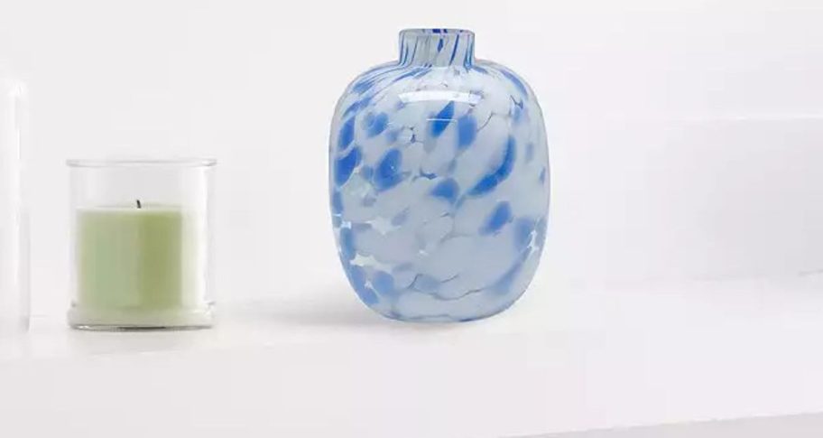 a blue and white confetti glass vase on a mantle