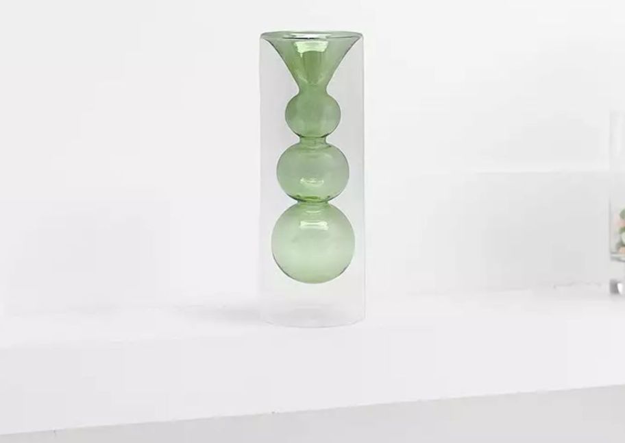 a green glass vase on a mantle