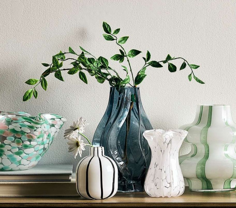 a grouping of glass vases on a mantle