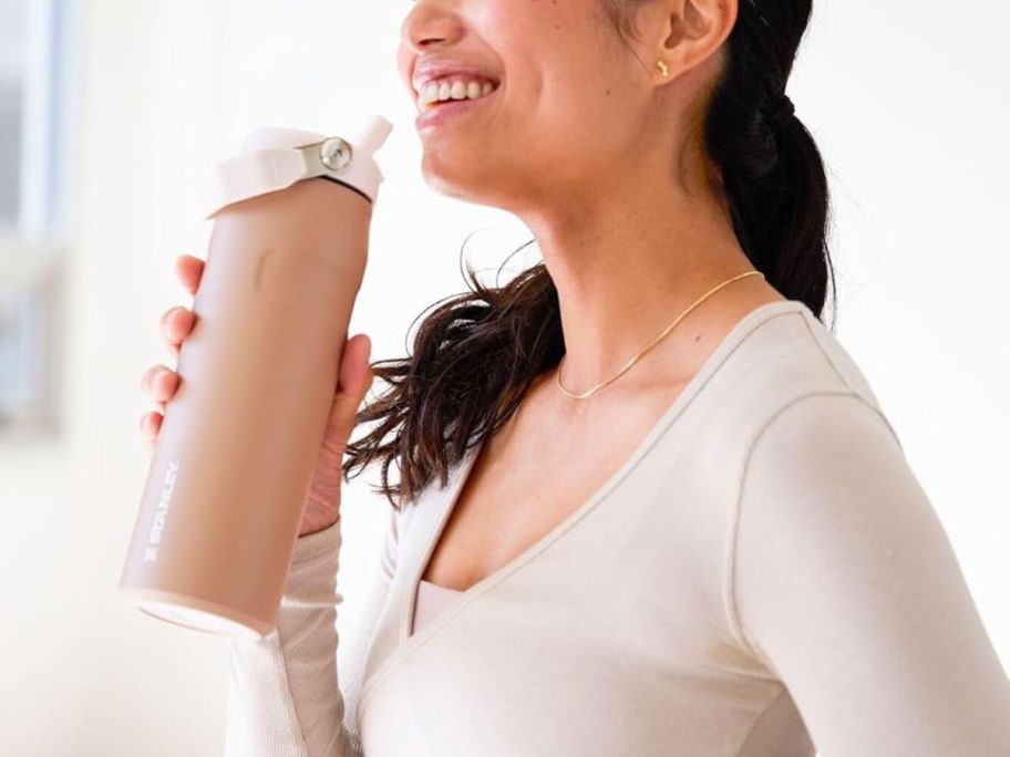 A woman holding a Stanley in Almond Rose